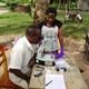 African researchers assessing worm prevalence in child samples through microscope