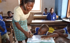 Teacher in classroom with pupil in Ghana.jpg
