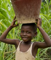 Boy in sub-Saharan Africa carrying a water bucket on his head