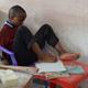 Boy writing with foot in classroom 